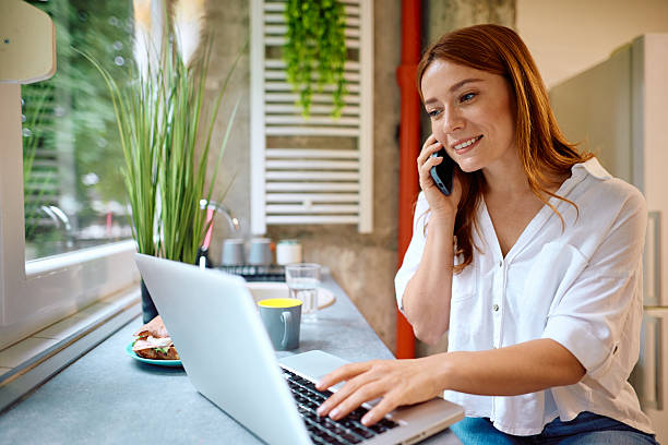 istock Young woman working from home using laptop and talking on the phone 2215081000