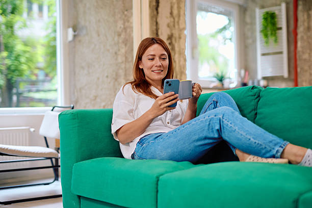 istock Woman relaxing on the sofa using smartphone and drinking coffee 2215081336