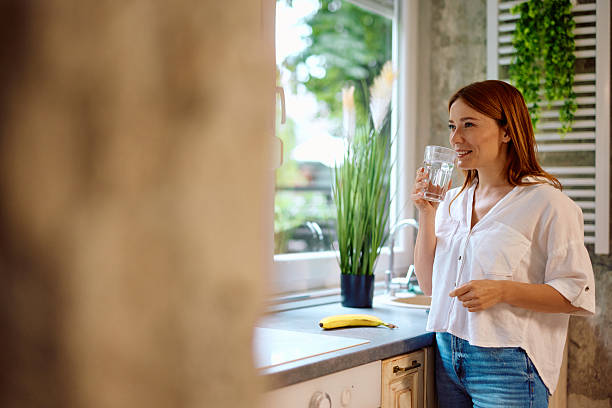 istock Young woman drinking water in the kitchen 2215081545