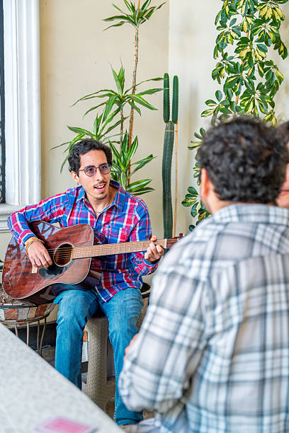 istock Young man playing guitar for his friends at home 2215090489