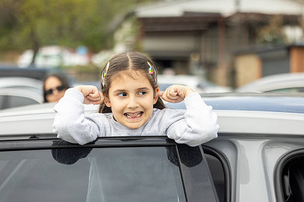 A girl making a funny pose on the car