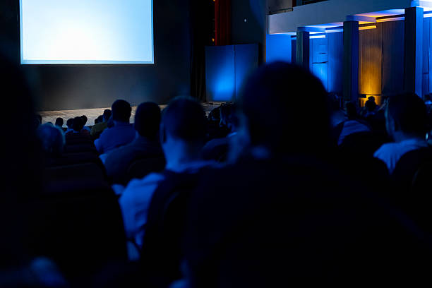 istock Audience engaged in presentation at darkened venue during evening event 2215091892