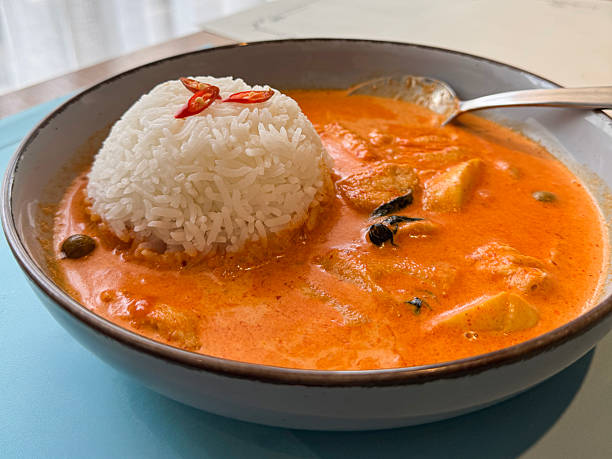 Stock photo showcases a flavorful Thai red curry featuring tender white chicken simmered in a creamy coconut sauce, served with fragrant jasmine rice. A classic example of authentic Thai cuisine, the dish combines rich spices and smooth textures for a comforting meal