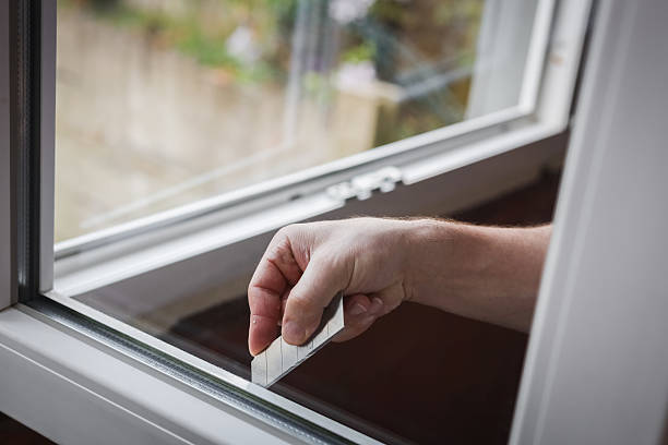 istock One young worker cleans the window glass with a construction knife. 2215093293