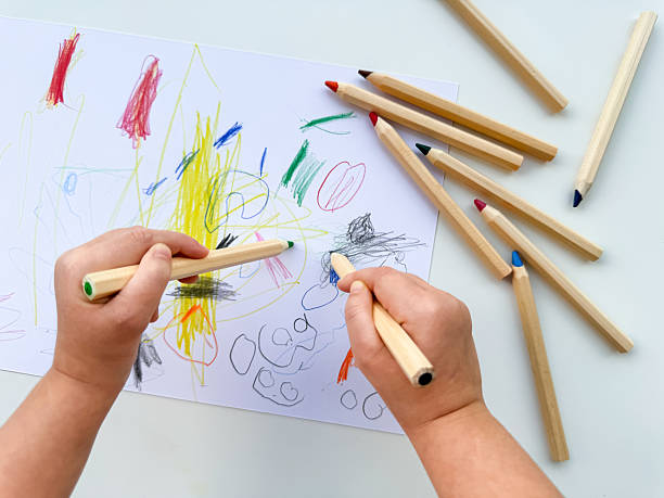istock Child drawing with colorful pencils on white paper 2215093468