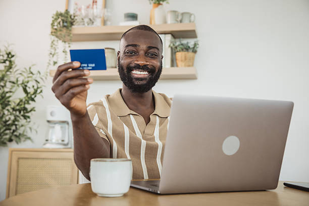 istock Man shopping online with a credit card using a laptop at home 2215094270