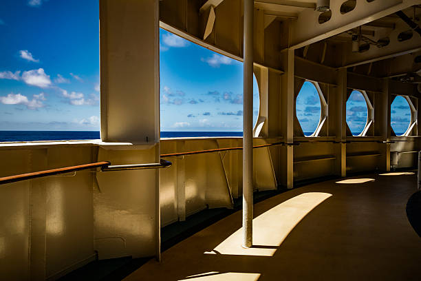 Cruise ship windows, no glass, nice composition, taken on a less-traveled deck of a cruise ship, nice sunny day at sea, blue sky, beautiful blue ocean, combination of shadow and sunlight.  Windows shaped in circles and rectangles.