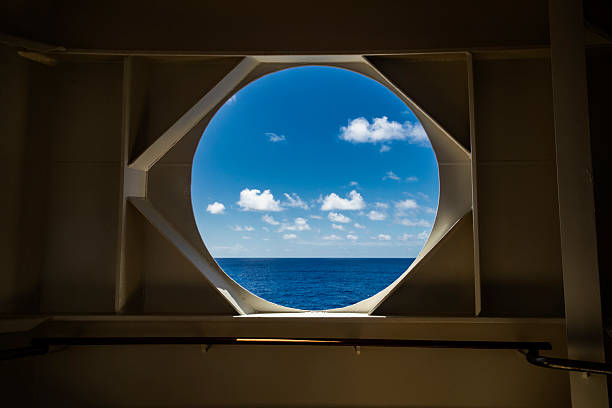 Cruise ship window, no glass, taken on a less-traveled deck of a cruise ship, nice sunny day at sea, blue sky, beautiful blue ocean.