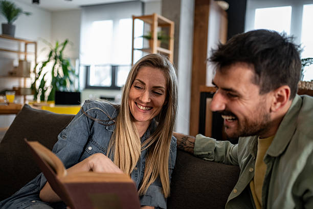 istock Couple reading a book together and having fun at home 2215098979