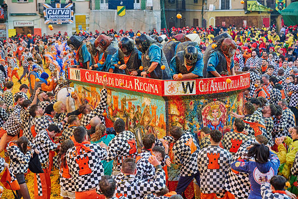 Ivrea, Italy - March 02, 2025: groups in traditional dressing take part in the Battle of the Oranges, where a teams of orange handlers on foot throw oranges (representing old weapons and stones) against aranceri of the team \