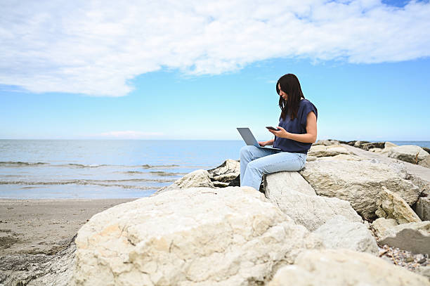 istock Freelancer working on laptop and smartphone by the sea 2215109684