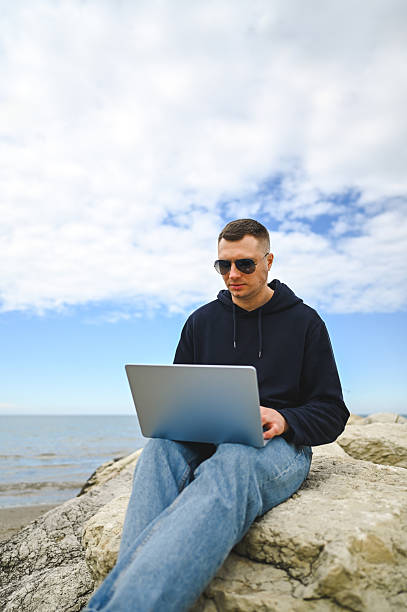 istock Freelancer working on laptop by the sea 2215109811