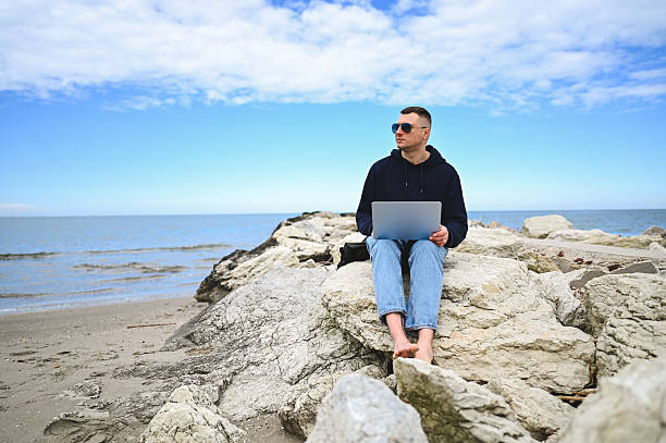 istock Freelancer working on laptop at the beach 2215109845