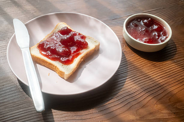 istock Spreading strawberry jam on toast bread on pink plate 2215110514
