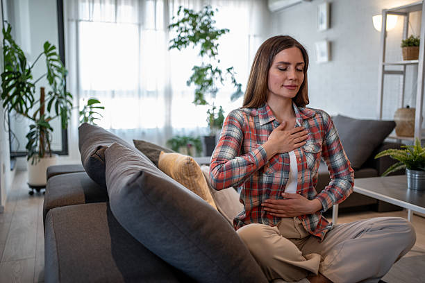 istock Serene woman practicing deep breathing exercise at home 2215110795