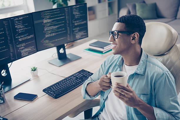 istock Photo of cheerful clever geek guy found tech solution developer it specialist coffee pause when he coding indoors workspace office 2215112096