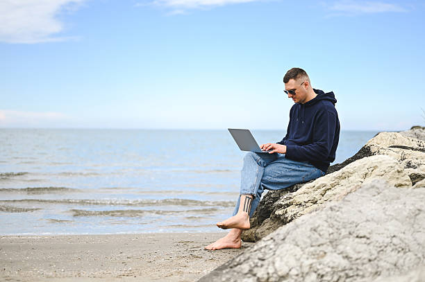 istock Freelancer working on laptop at beach enjoying freedom 2215114190