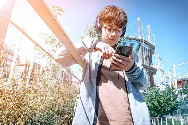 istock Boy wearing headphones using phone in urban park 2215116643