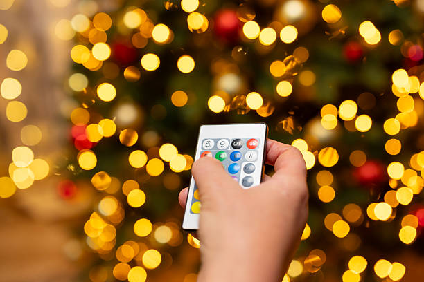 istock Woman's hand with RGB remote control near Christmas tree 2215117243