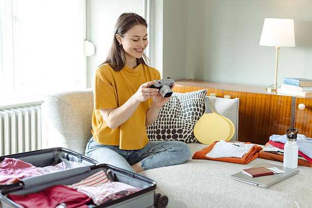 istock Woman packing suitcase while holding a camera in a stylish home 2215119436
