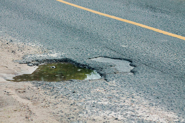 istock Old asphalt road with dangerously damaged asphalt that has potholes dangerous for the transit of motor vehicles 2215120657