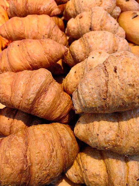 croissants various textures and colors displayed at bakery during morning rush. close up.