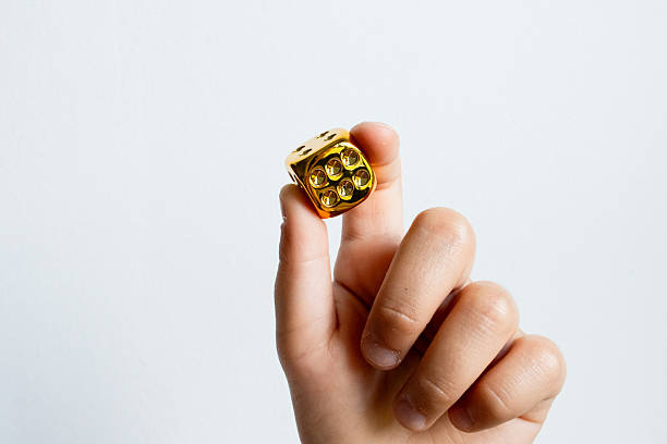 istock Hand holding a golden die against white background 2215141993