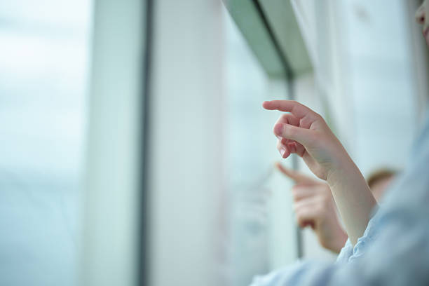 Close up Two girls pointing and drawing something on big glass window while surrounded by a soft atmosphere.