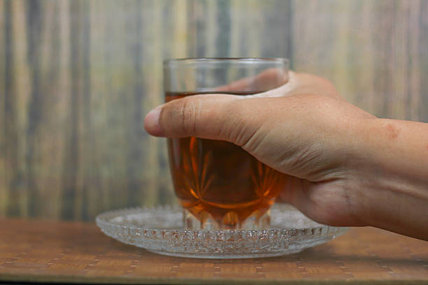 man's hand takes a glass of warm tea