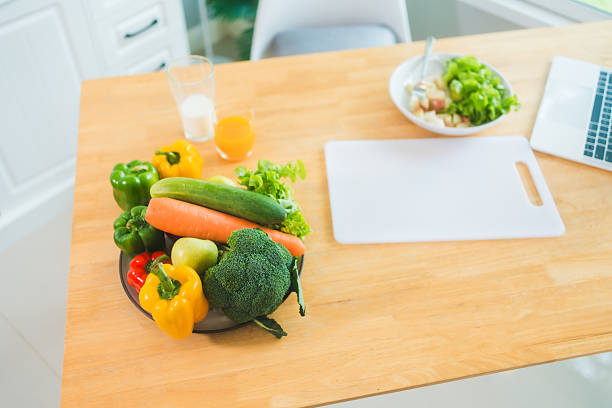 istock A clean kitchen setup featuring fresh vegetables, a salad bowl, juice, and a laptop. The scene promotes healthy eating, productivity, and a balanced lifestyle with natural, nutritious food choices 2215151463