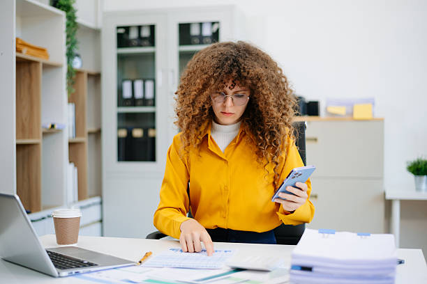 istock woman using smartphone at office desk with charts and laptop, symbolizing focus, communication, business data and productivity 2215153768