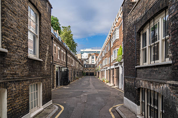 istock Narrow Alley Between Classic Brick Buildings Under Clear Sky, Featuring Historic Architecture and Small Residential Windows in a Peaceful Urban Setting. 2215156330