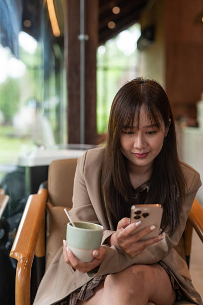 istock woman drinking coffee in cafe and using phone 2215159975