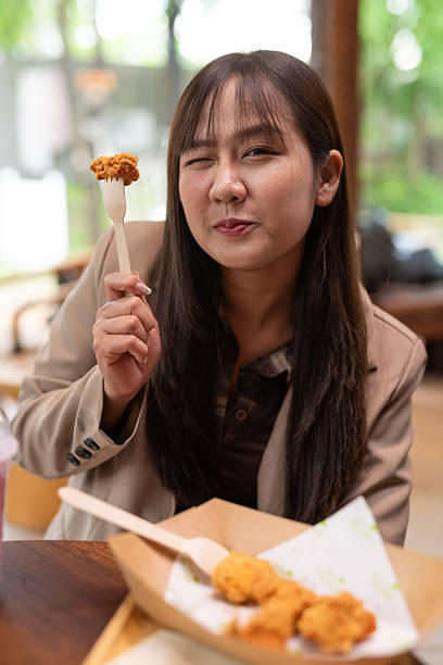 istock young woman eating fried chicken 2215160347