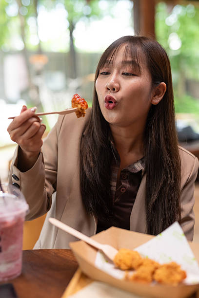 istock young woman eating fried chicken 2215160405
