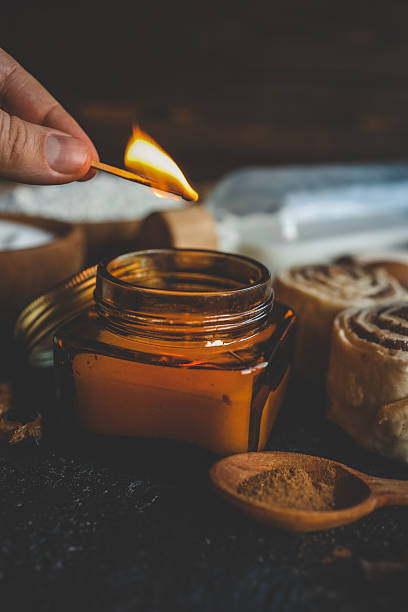 istock A hand lighting a candle in a cozy baking setup with cinnamon buns, flour, sugar, and eggs on a dark surface, ideal for warm kitchen scenes 2215161032
