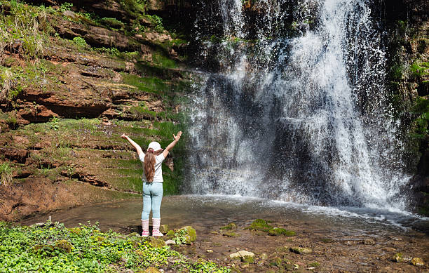 istock Kid  standing in front of a waterfall in the mountain 2215163569