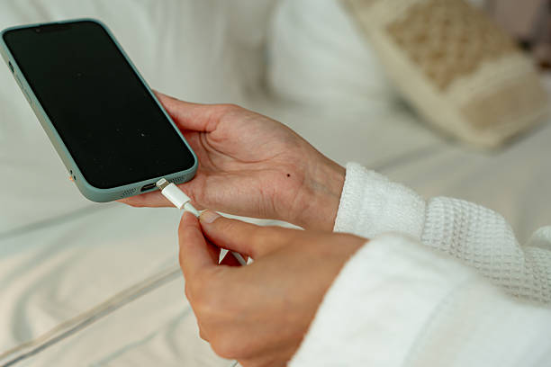 istock Woman in bathrobe charging smartphone on bed 2215163654
