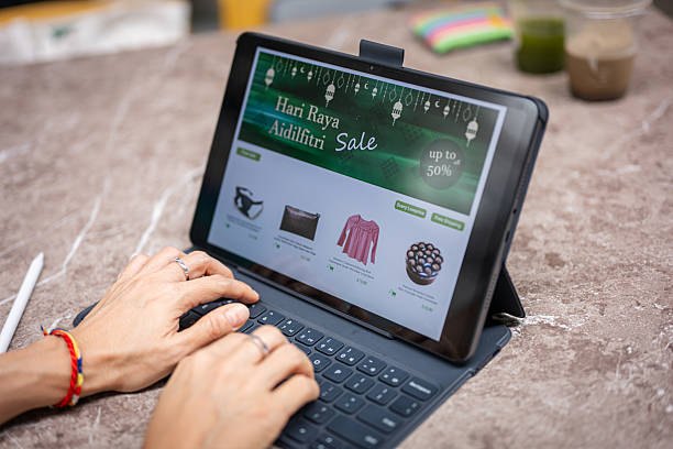 Close-up of a woman using a digital tablet for RAYA online shopping at home.