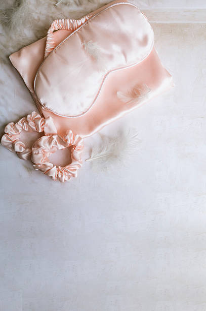istock Silk sleeping mask and  feathers on  pink background 2215164462