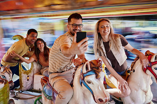 istock Happy friends taking a selfie during carousel ride at amusement park. 2215166724