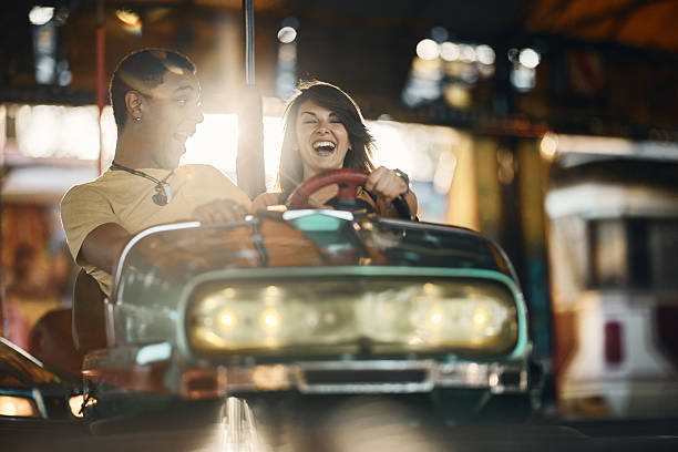 istock Carefree couple having fun while driving bumper car at amusement park. 2215167536