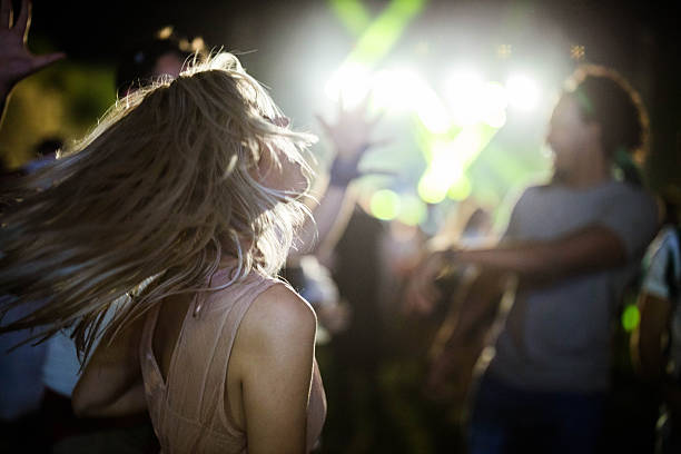 Carefree woman having fun while dancing on music concert by night.