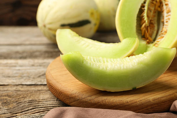 istock Fresh cut honeydew melon on wooden table, closeup. Space for text 2215169231