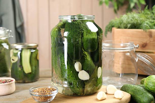istock Making pickles. Fresh cucumbers and spices in jars on wooden table 2215170457