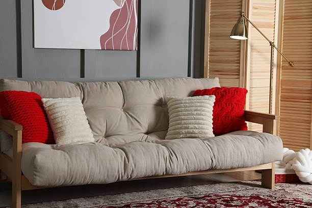 Wooden folding screen, comfortable sofa with pillows and lamp in room