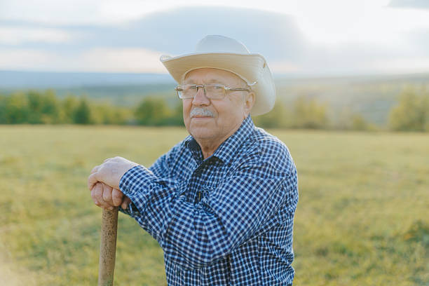 istock Weathered Farmer Standing in Countryside Field During Sunset Reflection 2215172901