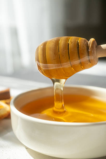 istock honey dripping from a wooden spoon 2215173139