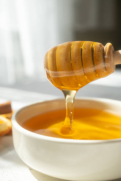 istock honey dripping from a wooden spoon 2215173179