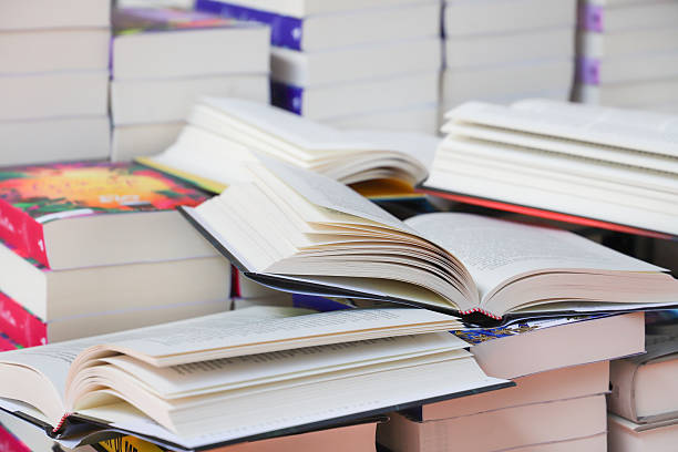 istock stack of books, close up. Open book on the table in library. Back to school concept. Open book on table with blur bookshelf background 2215174408